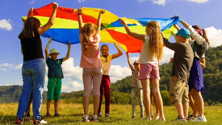 a group of children holding up a colorful kite
